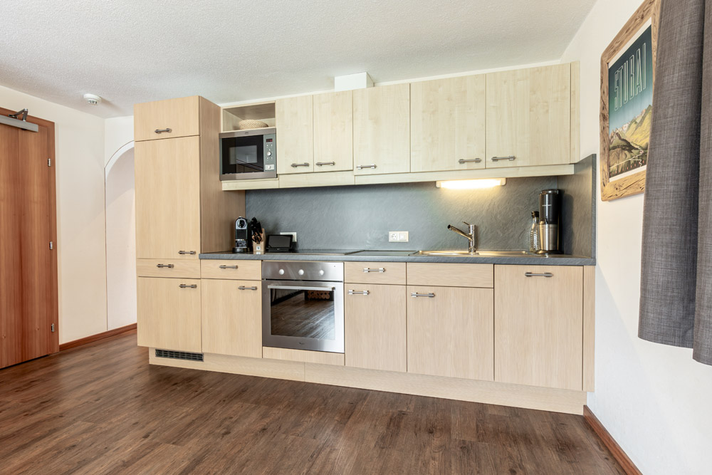 Moderne Küche mit hellen Holzschränken, eingebautem Ofen, Mikrowelle und Kaffeemaschine.