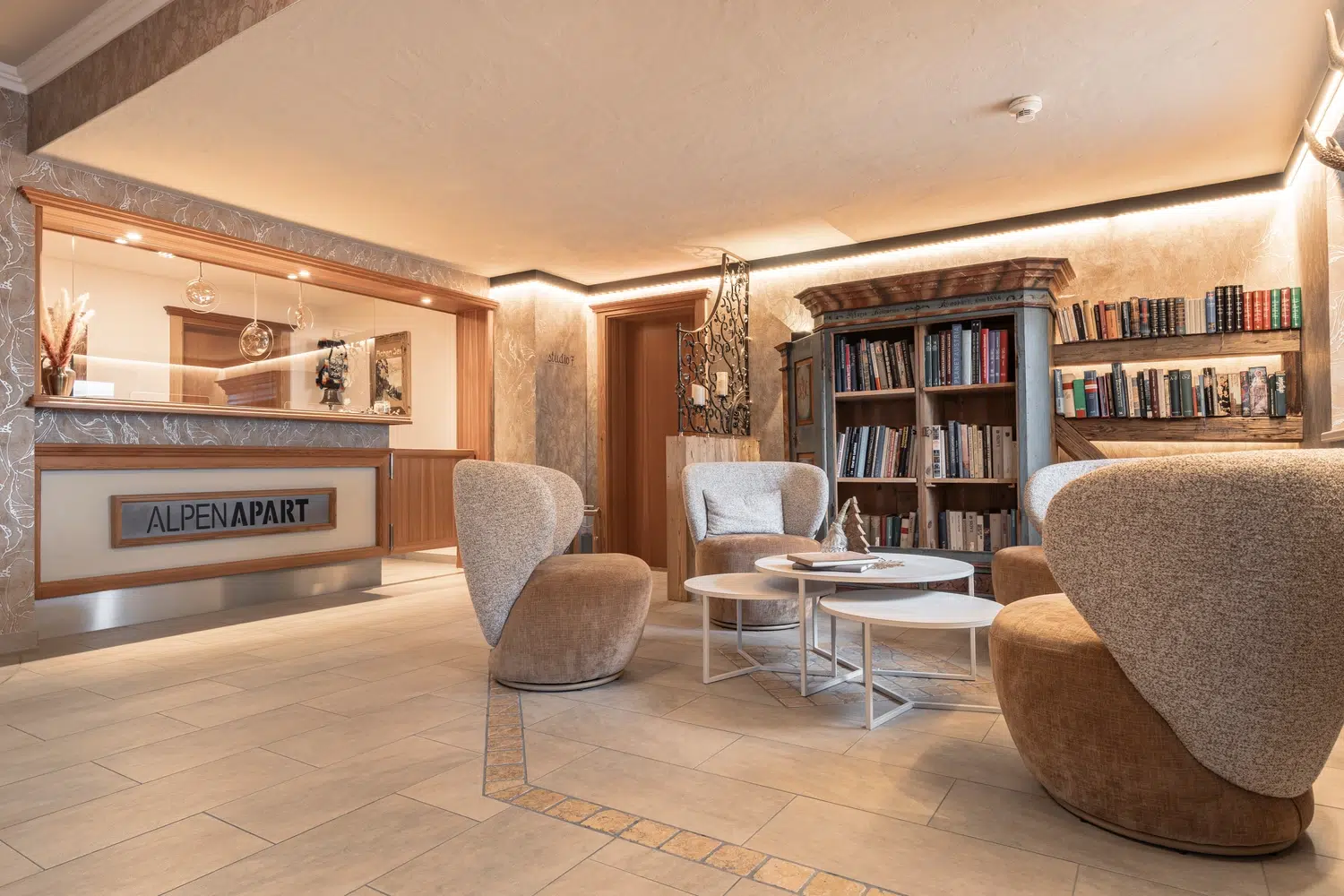 Gemütliche Hotellobby mit modernen Stühlen, Bücherregalen und Mimis Kinderspielwelt im Alpenapart in der Nähe.