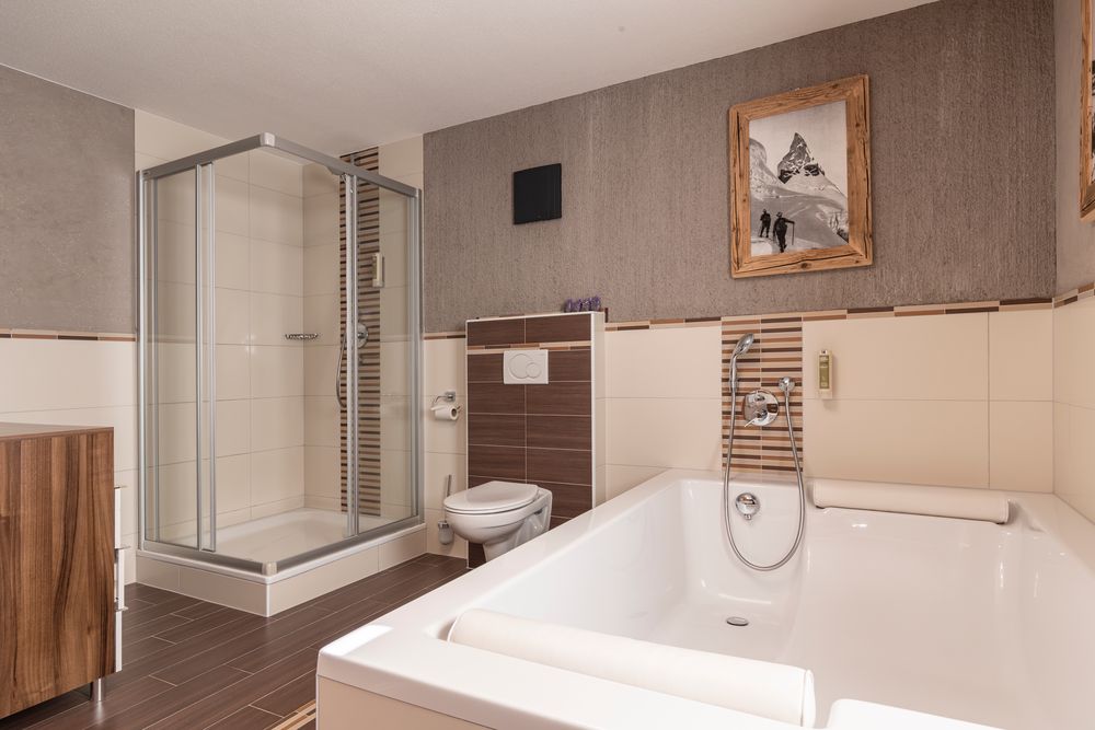 Modernes Badezimmer mit Badewanne, Dusche, Toilette, Holzakzenten und einem gerahmten Foto an der Wand.